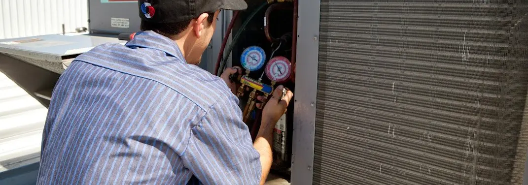 HVAC technician servicing a condenser unit in Dickinson