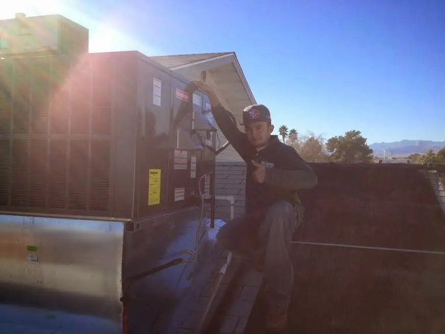 HVAC technician performing AC Tune-Up on a rooftop unit in Dickinson